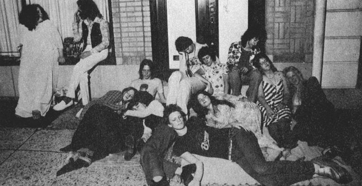 Black-and-white photo of teenagers sitting and lying on the sidewalk in the 1970s