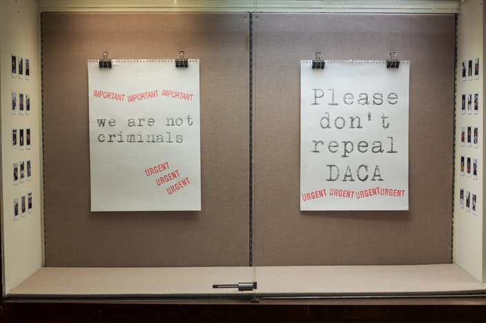 Two large sheets of white paper reading, 'we are not criminals' and 'Please don't repeal DACA' clipped to a board. Red stamps read, 'IMPORTANT' and 'URGENT'