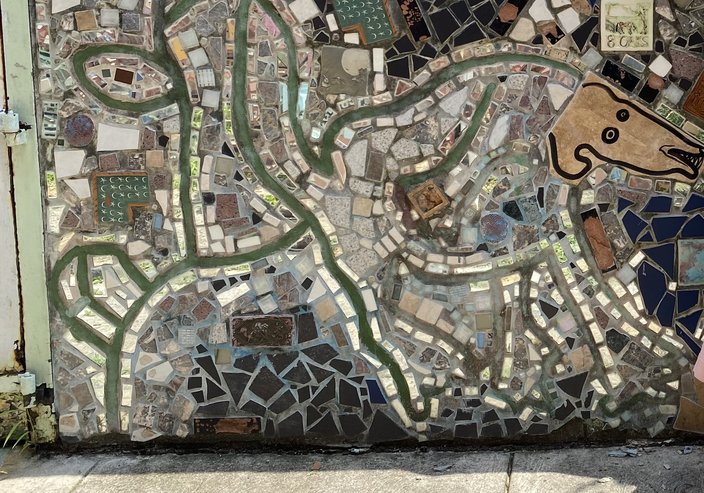 A mixed-media mosaic on a South Philly street features a dog