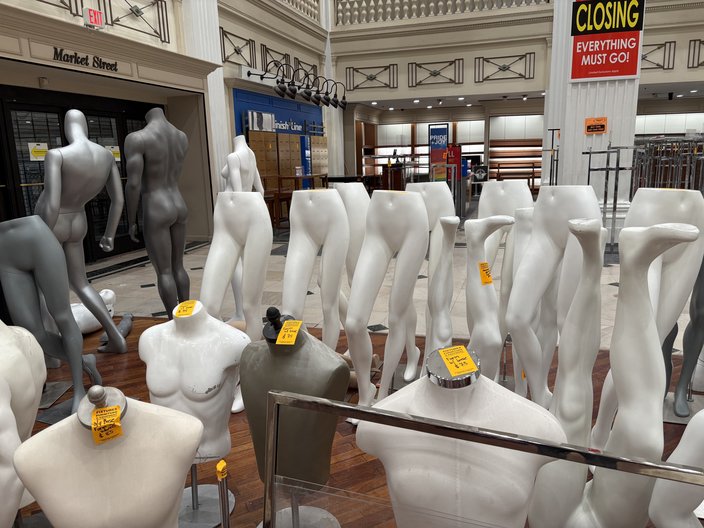 White and black mannequin torsos, legs and full forms stand in a cluster on a department store floor