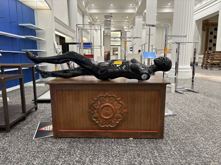 A black mannequin without arms lays on a brown desk