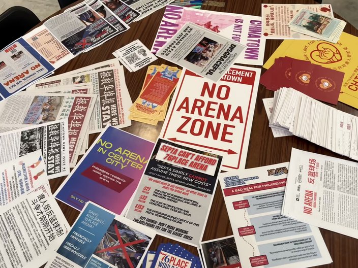 Flyers, pamphlets and postcards from the No Arena in Chinatown protest movement. A large red printout in the center reads 'No Arena Zone'