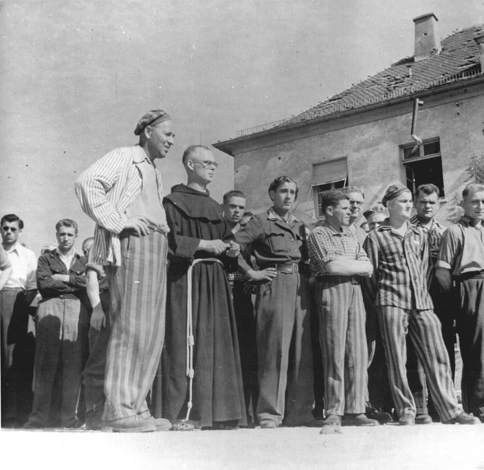 Holocaust survivors, some still in striped concentration camp uniforms, stand at a displaced persons camp in Heilbronn, Germany.