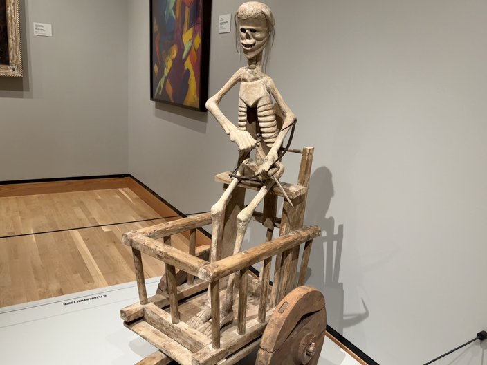 A skeleton inside a wooden cart holds a bow and arrow