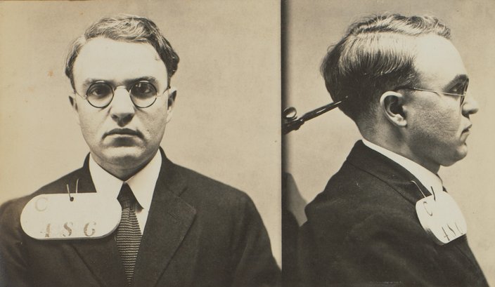 Black-and-white mugshots of a man in glasses and a suit.