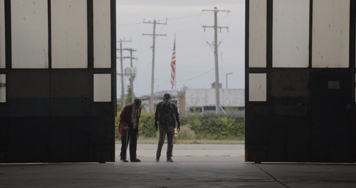 Two men stand in the middle of an airplane hangar opening.