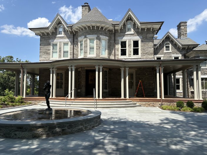 Maguire Hall, a gray two-story mansion with white pillars and a fountain