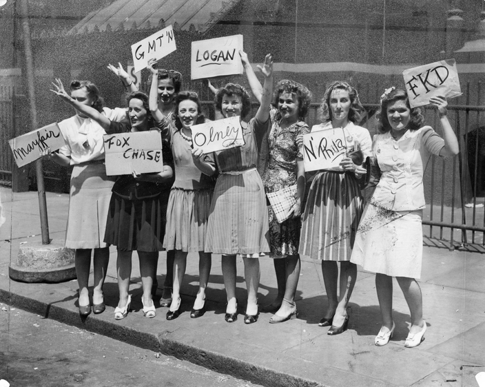 Black and white photo of eight women holding handwritten signs reading "Mayfair," "Fox Chase," "GMT'N," "Logan," "Olney," "FKD" and "N' Phila."