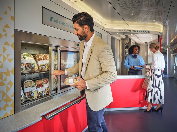 Man in a tan blazer and blue jeans grabs a sandwich from a grab-and-go section on the new Amtrak Acela train