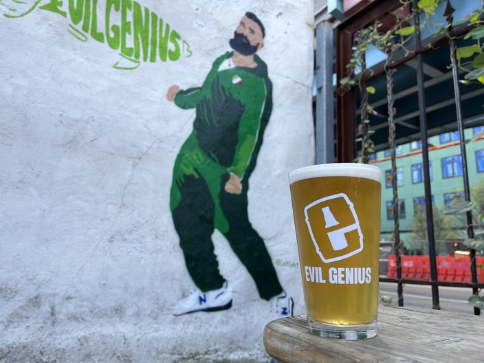 Graffiti of Jason Kelce in a green tracksuit on a white wall with a beer in front of it