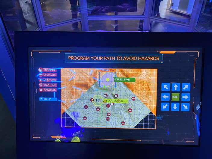 Interactive display at the Franklin Institute, with a digital screen reading, "Program your path to avoid hazards"