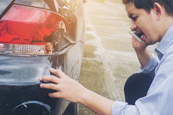 Limited - Man looking at damage from car accident