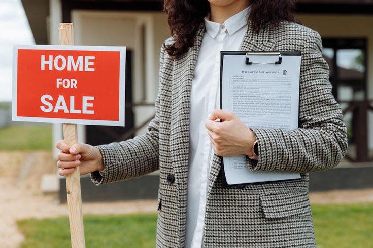Home for Sale sign held by real estate agent