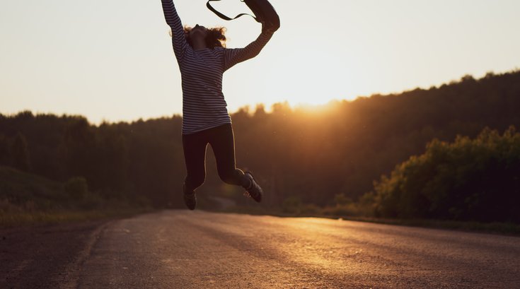 Woman jumping in street with sunset