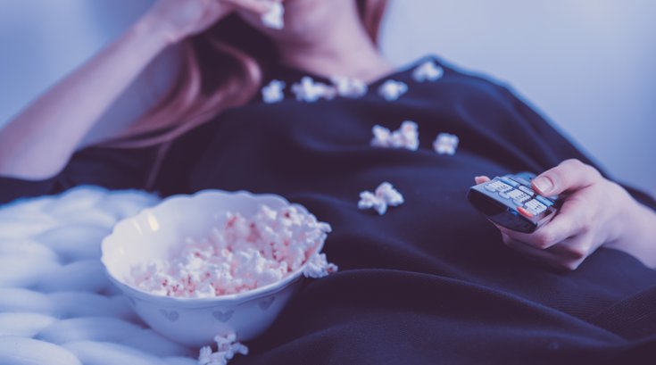 Woman eating popcorn watching tv