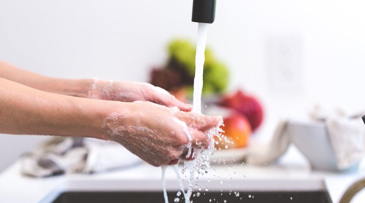 Person washing their hands in kitchen sink