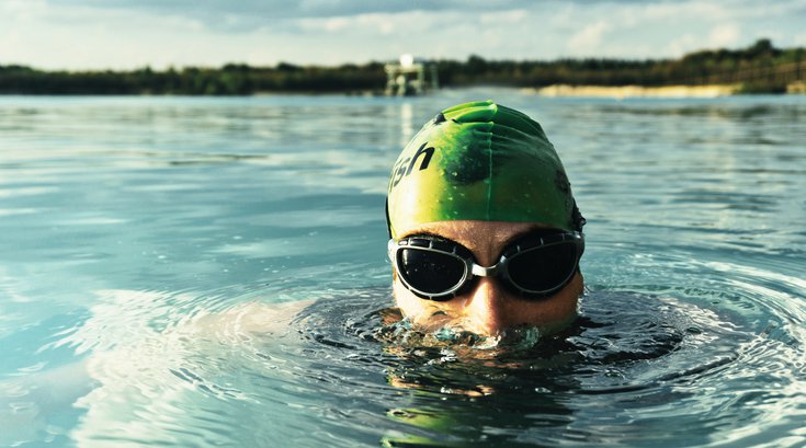 Man swimming in a lake with goggles