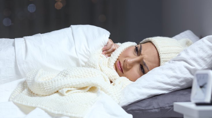 Woman suffering cold in a bed in winter