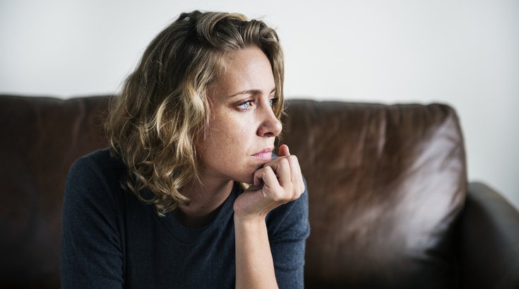 Woman deep in thought on a sofa