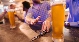 Limited - Man reaching for glass of beer and friend stopping him