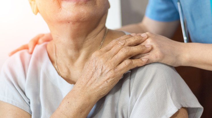 Elderly female hand holding hand of young caregiver at nursing home.