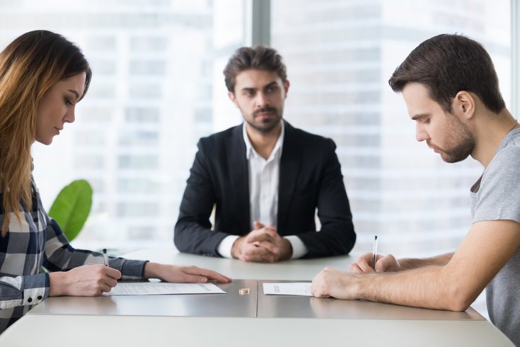 couple signing decree papers getting divorced in lawyers office