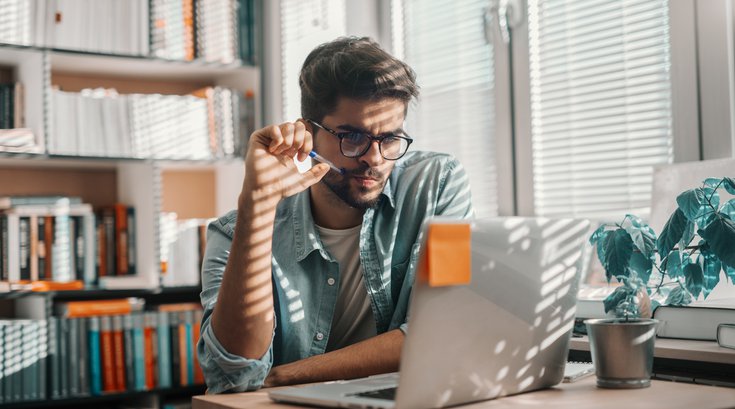 Purchased - Person sitting at desk in library using laptop