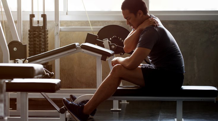 Man sitting on weight bench with injury