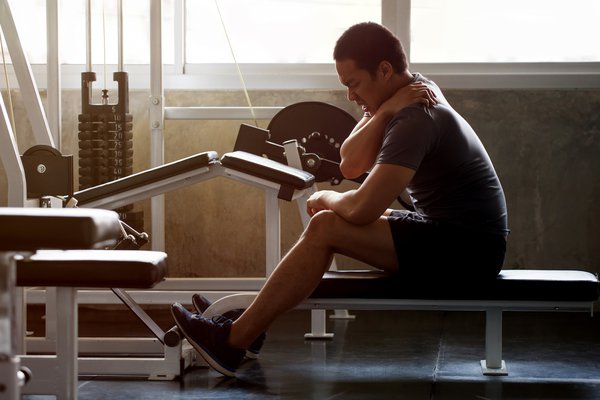 Man sitting on weight bench with injury