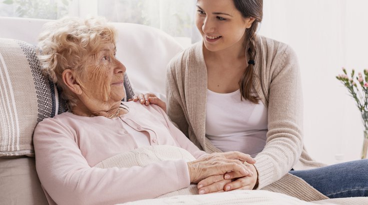 Young daughter supporting sick mother lying in hospital bed