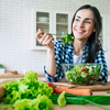Purchased - a woman eating a salad smiling in her kitchen