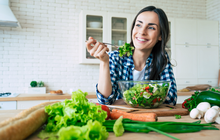 Purchased - a woman eating a salad smiling in her kitchen