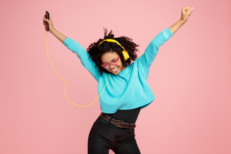 Purchased - Young woman dressed in casual clothes, glasses and headphones dance over pink background