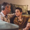 Father talking with teen son in living room