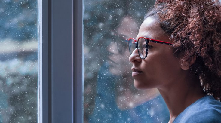 Purchased - Woman looking out a snowy window