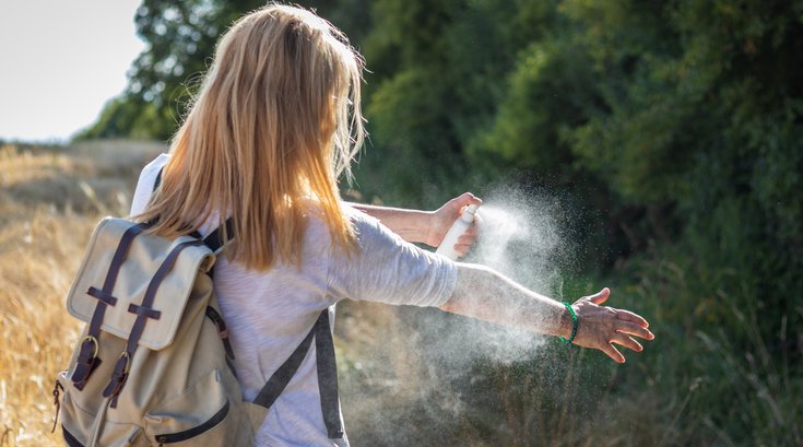 Purchased - Woman applying mosquito repellent on hand during hike in nature