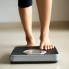 Female leg stepping on weigh scales.