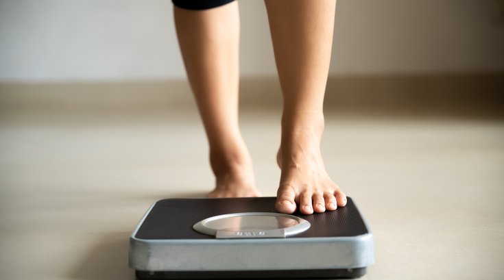 Female leg stepping on weigh scales.