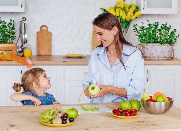 Smiling mother and daughter making fruit salad 