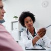 Purchased - Doctor talking with patient at desk in medical office