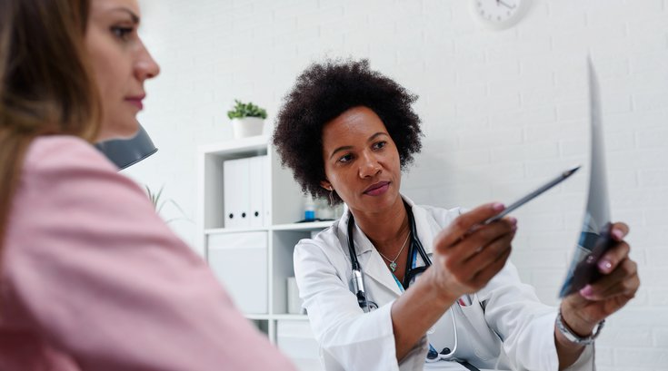 Purchased - Doctor talking with patient at desk in medical office