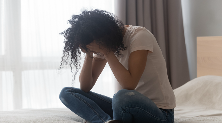 Purchased - Depressed woman sitting alone in bed