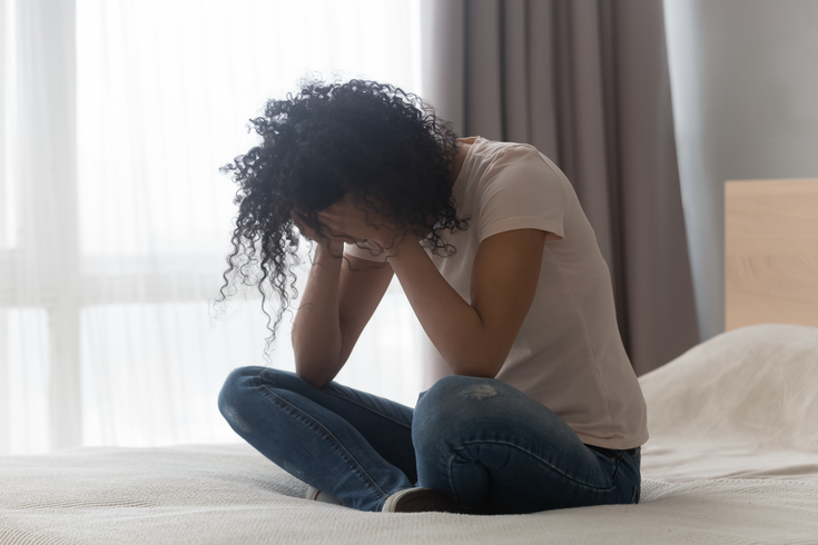 Purchased - Depressed woman sitting alone in bed