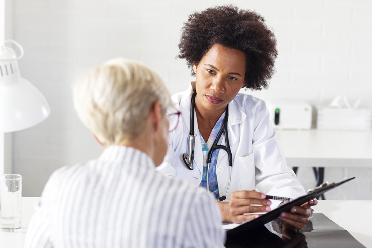 Purchased - Woman speaking with her doctor at a desk