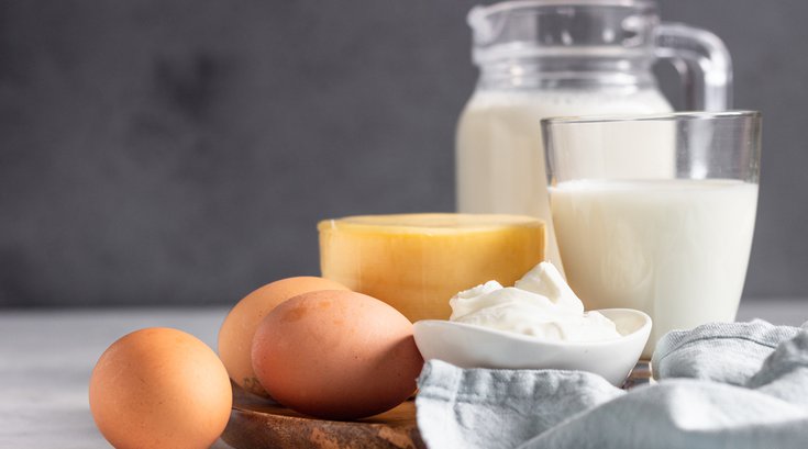 Different types of fresh dairy products and eggs on wooden plate.