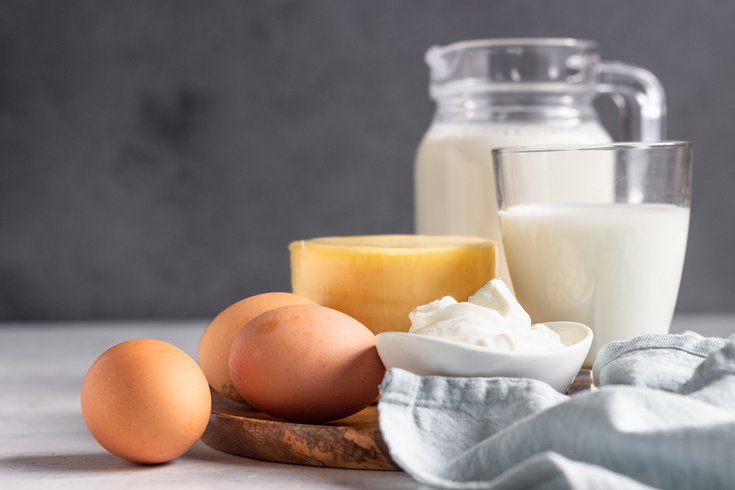 Different types of fresh dairy products and eggs on wooden plate.
