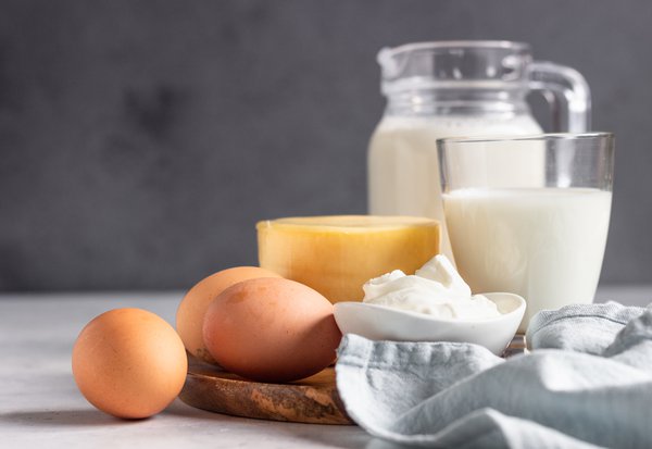 Different types of fresh dairy products and eggs on wooden plate.