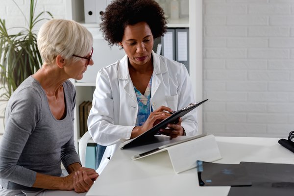 Purchased - A female doctor sits at her desk and chats to an elderly female patient