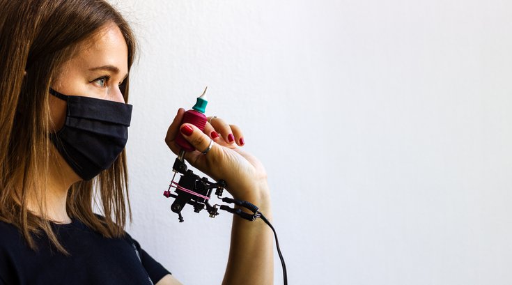 Purchased - Tattoo artist with face mask standing next to wall stock