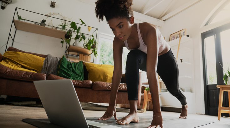 young woman working out from home, online workout on laptop
